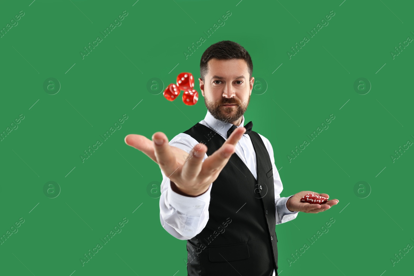 Photo of Professional croupier with dice and casino chips on green background