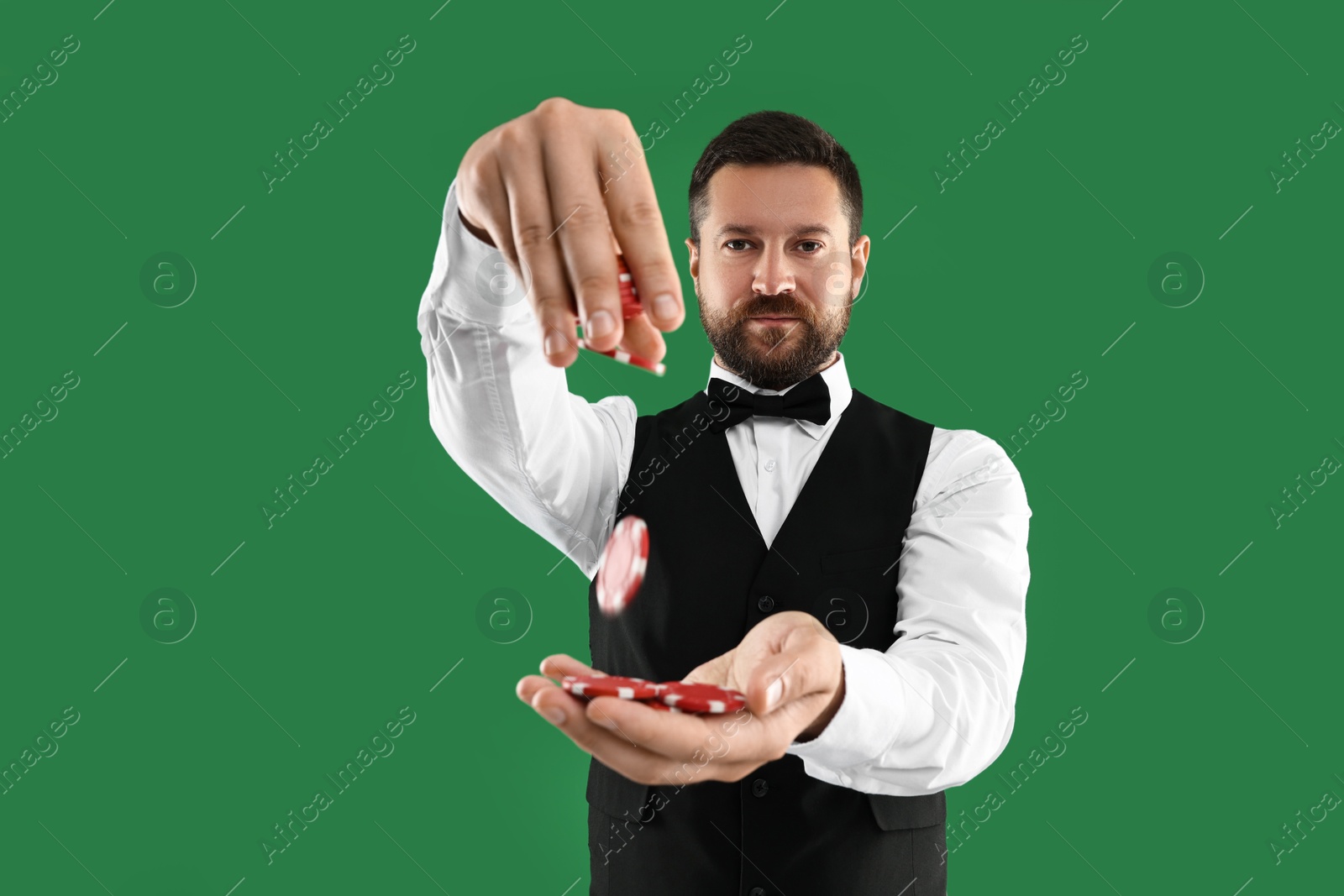 Photo of Professional croupier with casino chips on green background