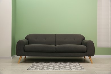 Photo of One stylish sofa near green wall indoors