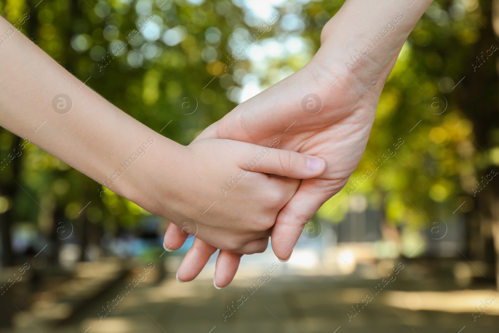 Photo of Mother and daughter holding hands in park, closeup