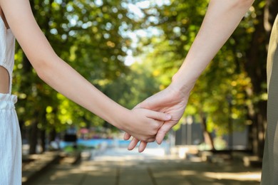 Photo of Mother and daughter holding hands in park, closeup