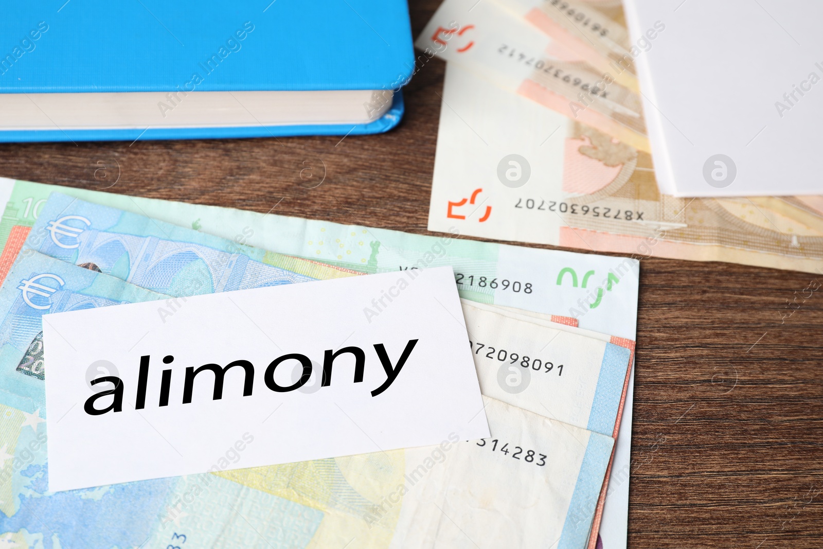 Photo of Alimony. Euro banknotes, blank card and notebook on wooden table, closeup