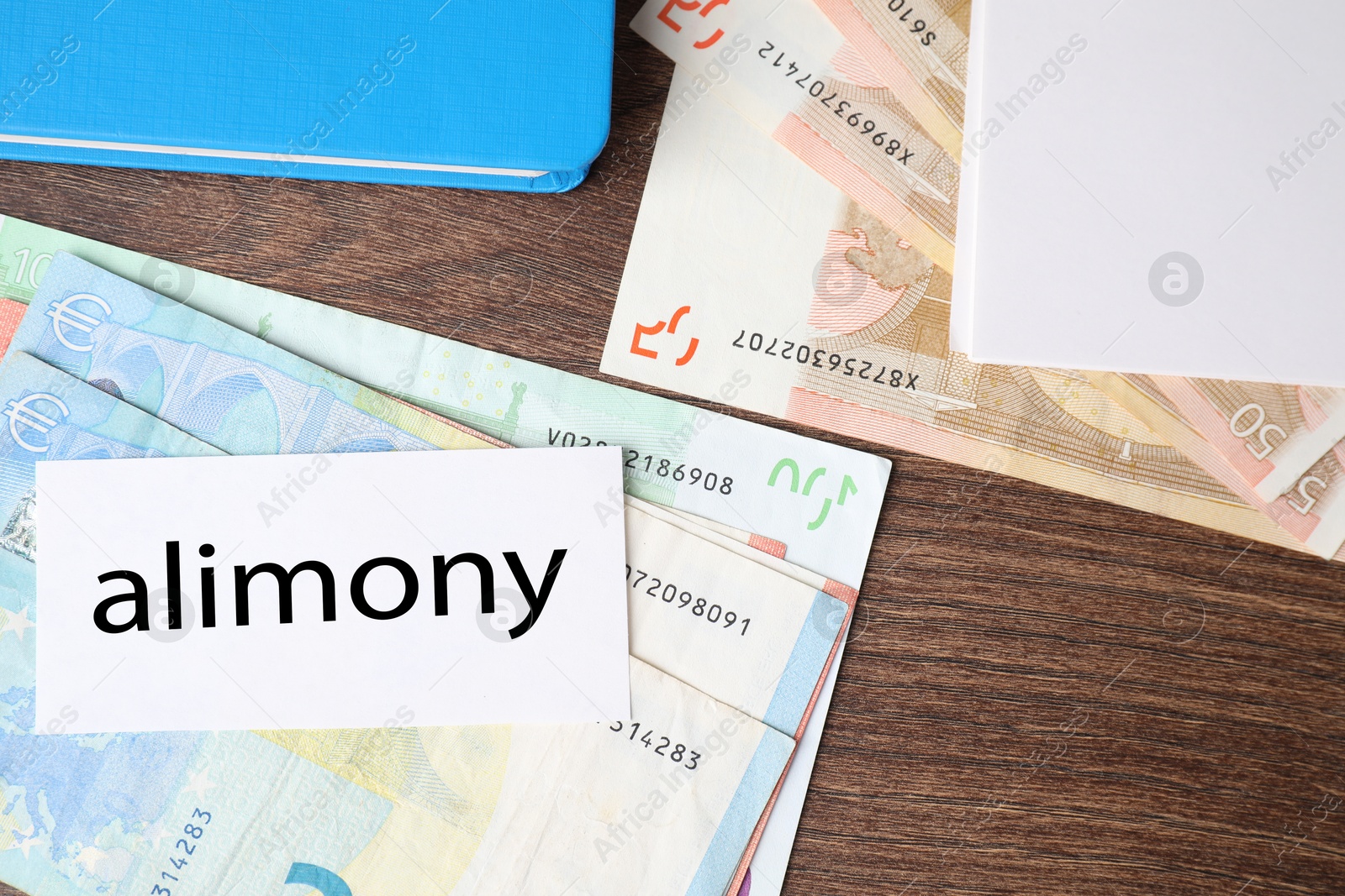 Photo of Alimony. Euro banknotes, blank card and notebook on wooden table, top view