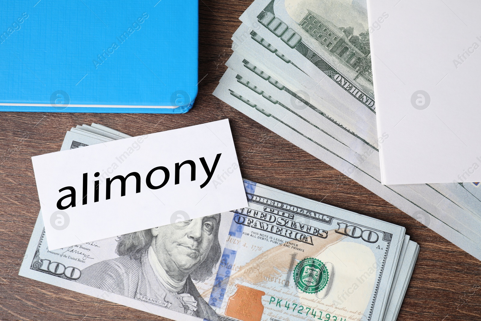 Photo of Alimony. Dollar banknotes, blank card and notebook on wooden table, top view