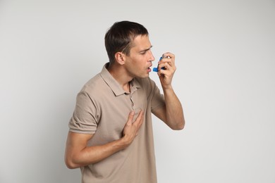 Photo of Man using asthma inhaler on light background