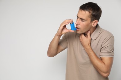 Photo of Man using asthma inhaler on light background, space for text