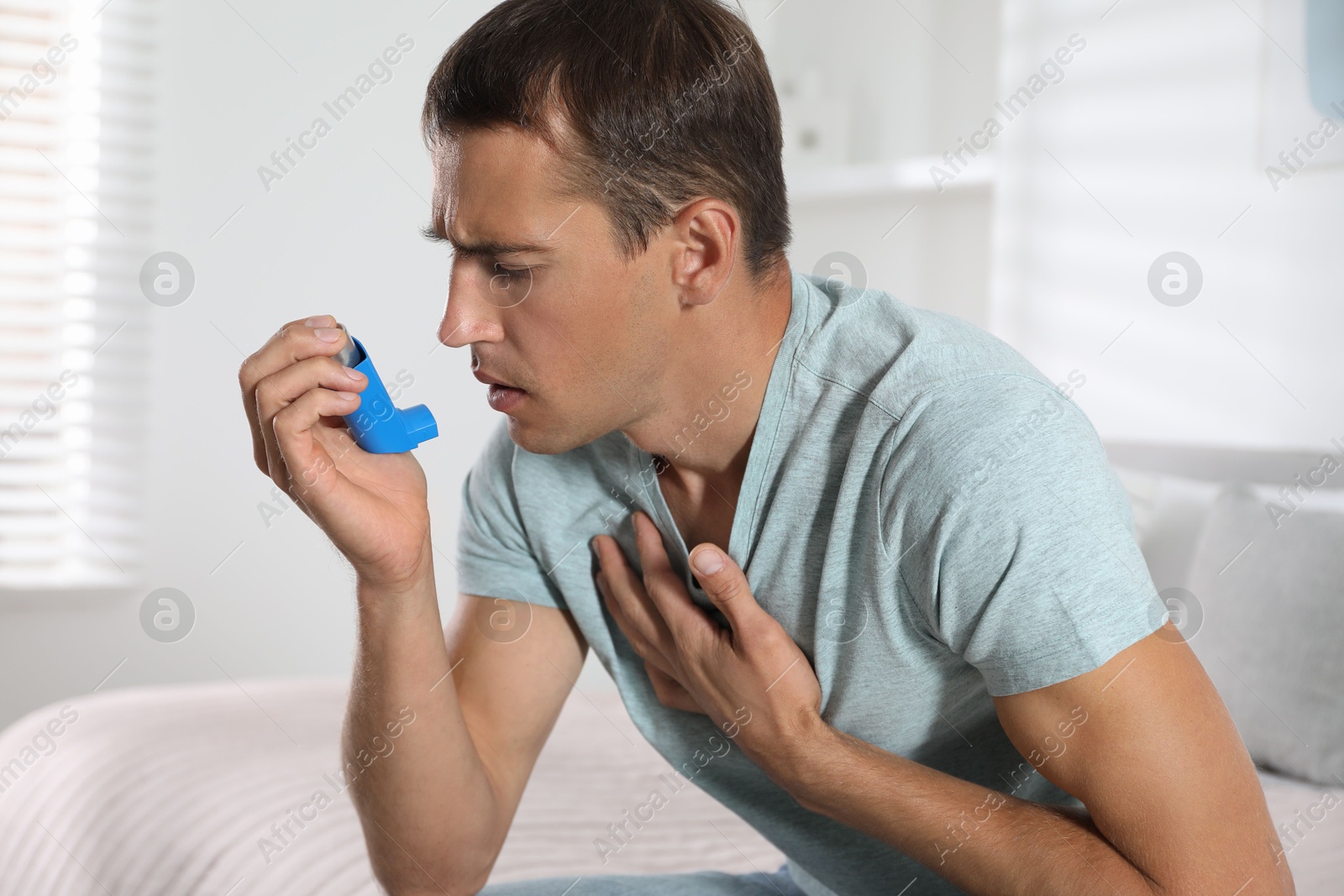 Photo of Man using inhaler at home. Asthma treatment