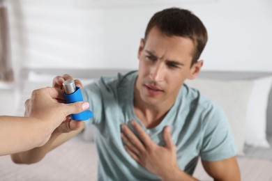 Man getting asthma inhaler at home, selective focus