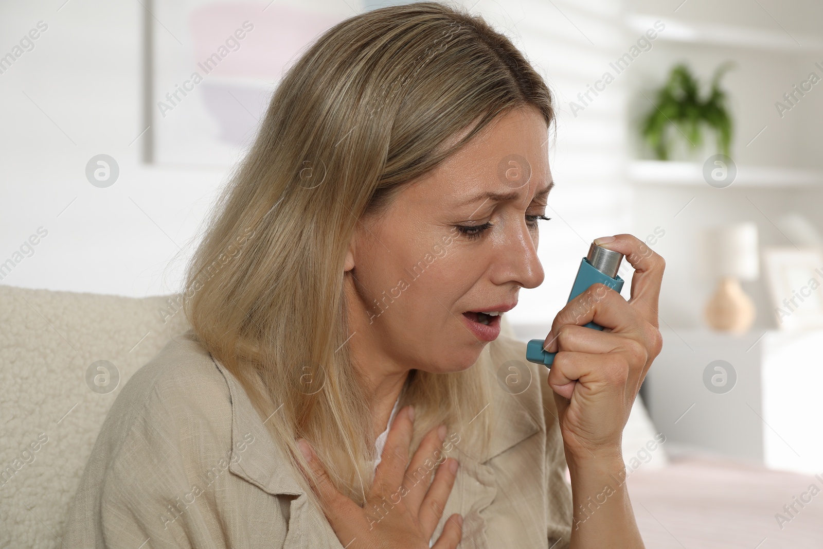 Photo of Woman using inhaler at home. Asthma treatment