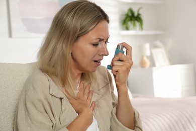 Photo of Woman using inhaler at home. Asthma treatment