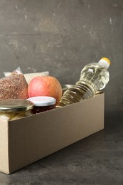 Photo of Different food products for donation in box on grey table