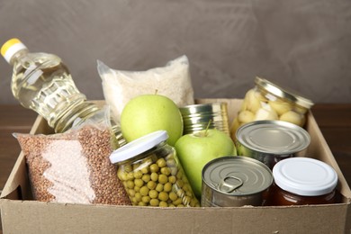 Photo of Different food products for donation in box on table, closeup