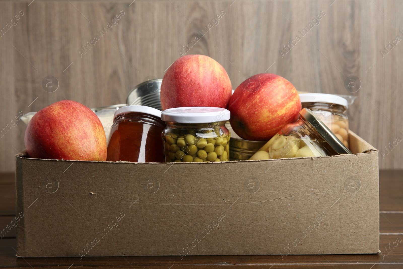 Photo of Different food products for donation in box on wooden table