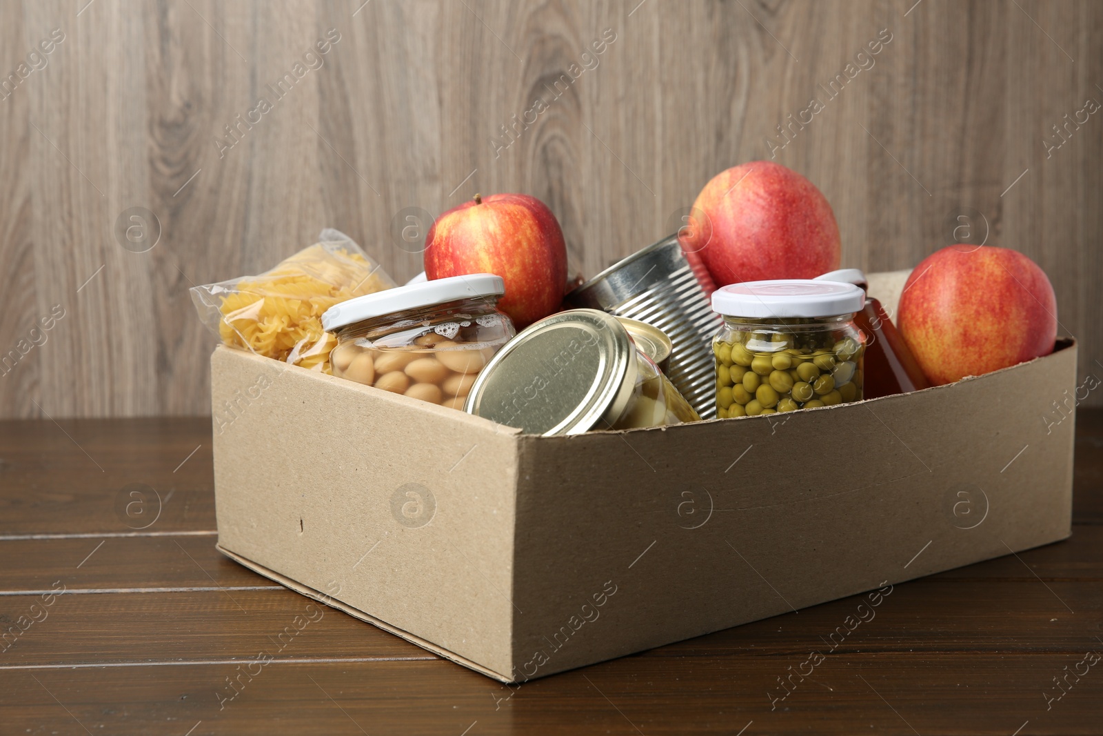 Photo of Different food products for donation in box on wooden table