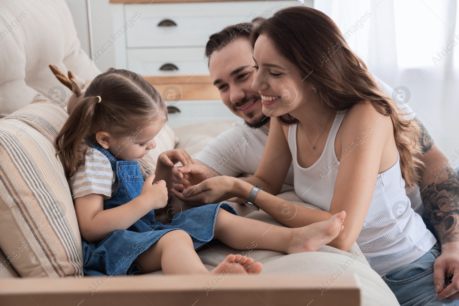 Photo of Happy family. Parents and their cute little daughter on sofa at home