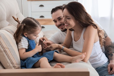 Photo of Happy family. Parents and their cute little daughter on sofa at home