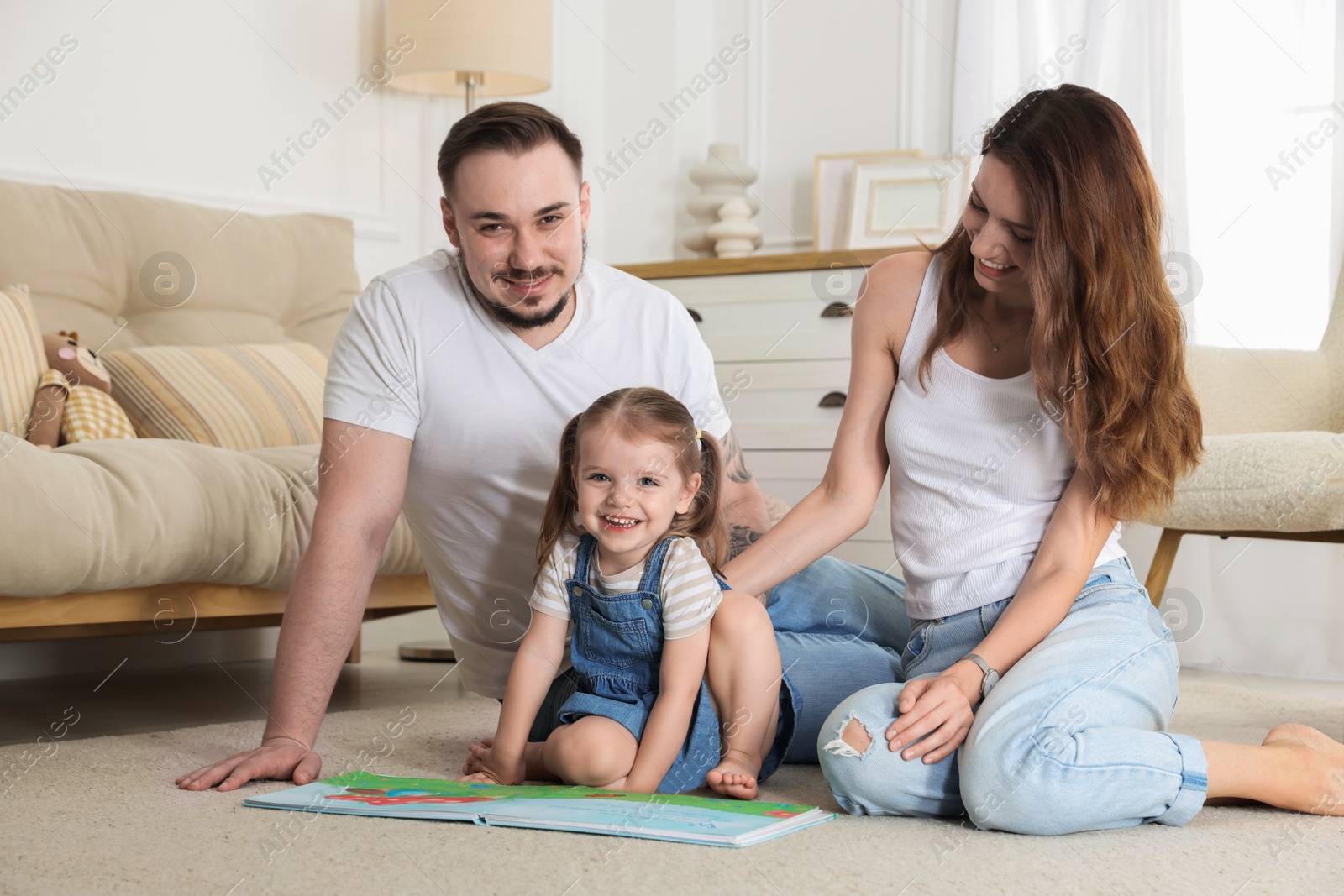 Photo of Happy family. Parents and their cute little daughter with book at home