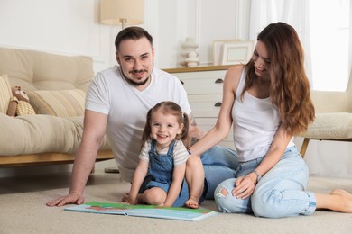 Photo of Happy family. Parents and their cute little daughter with book at home