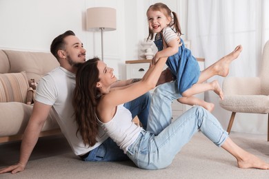 Photo of Happy family. Parents and their cute little daughter having fun at home