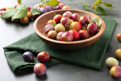 Photo of Ripe plums in bowl on grey table