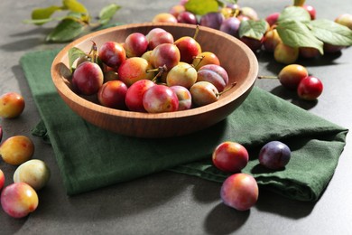 Photo of Ripe plums in bowl on grey table