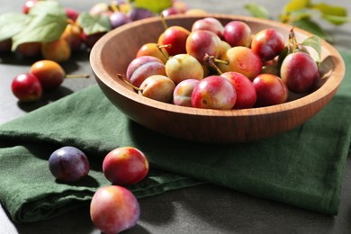 Photo of Ripe plums in bowl on grey table, closeup