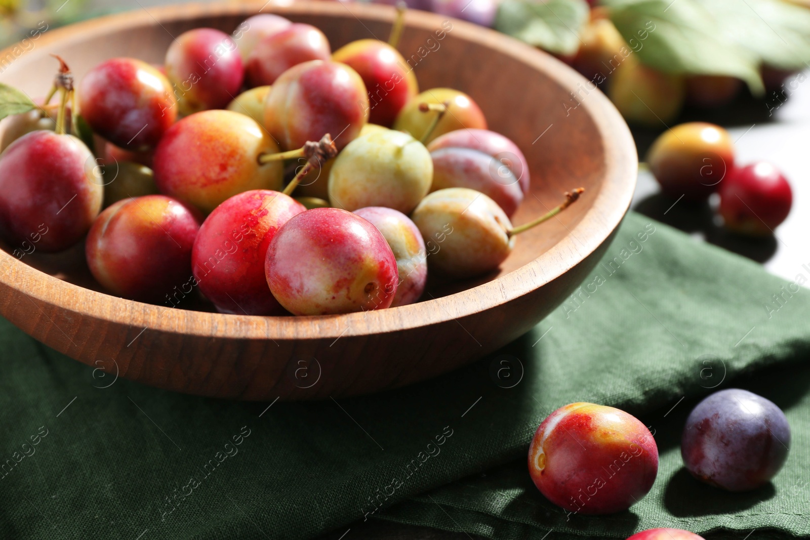 Photo of Ripe plums in bowl on grey table, closeup