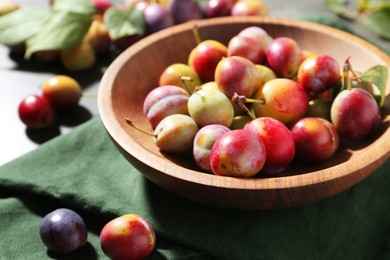 Photo of Ripe plums in bowl on grey table, closeup