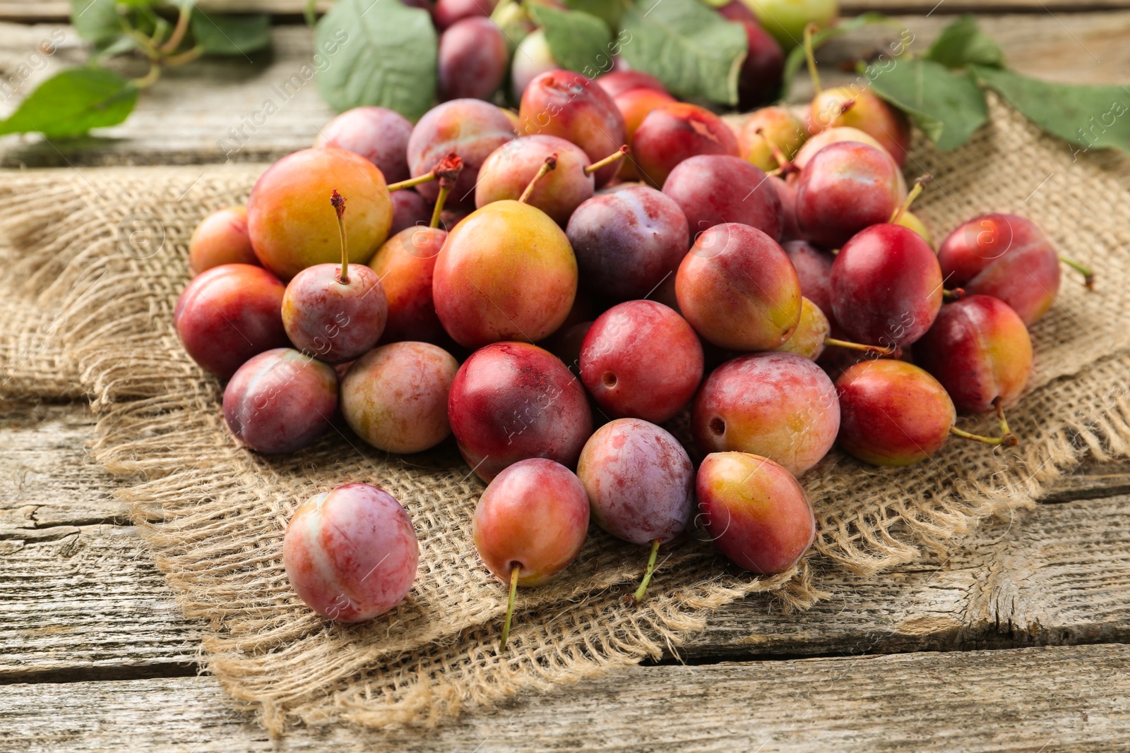 Photo of Pile of tasty ripe plums on wooden table