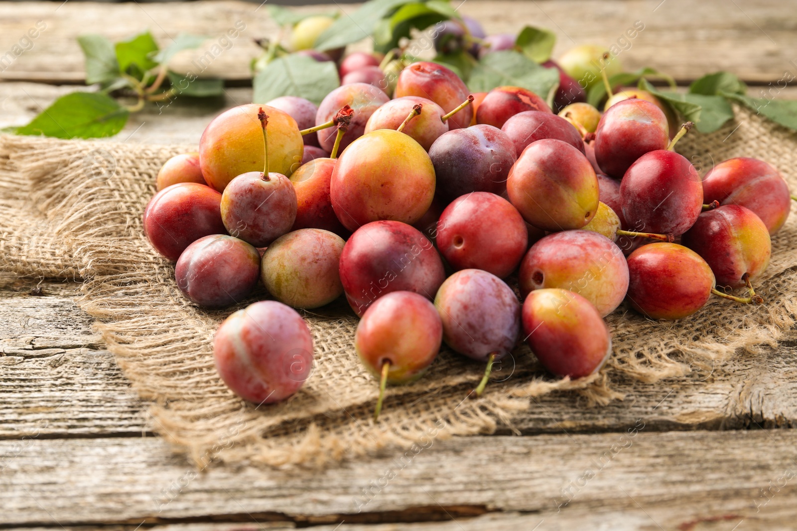 Photo of Pile of tasty ripe plums on wooden table