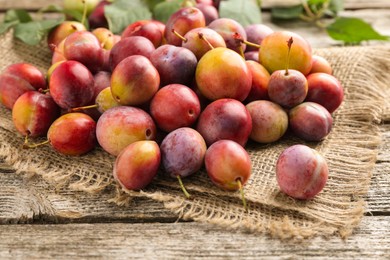 Photo of Pile of tasty ripe plums on wooden table