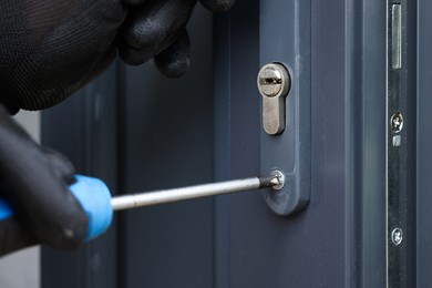 Photo of Repairman installing new door with screwdriver indoors, closeup