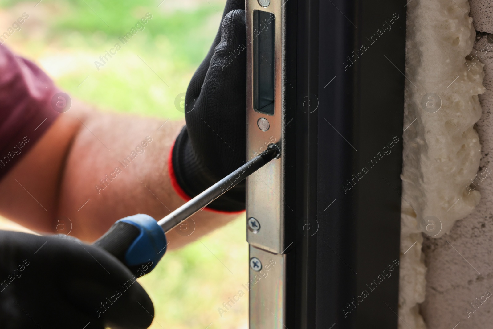 Photo of Repairman installing new door with screwdriver indoors, closeup