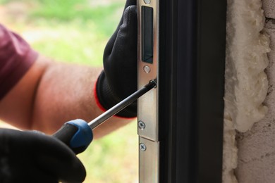 Photo of Repairman installing new door with screwdriver indoors, closeup