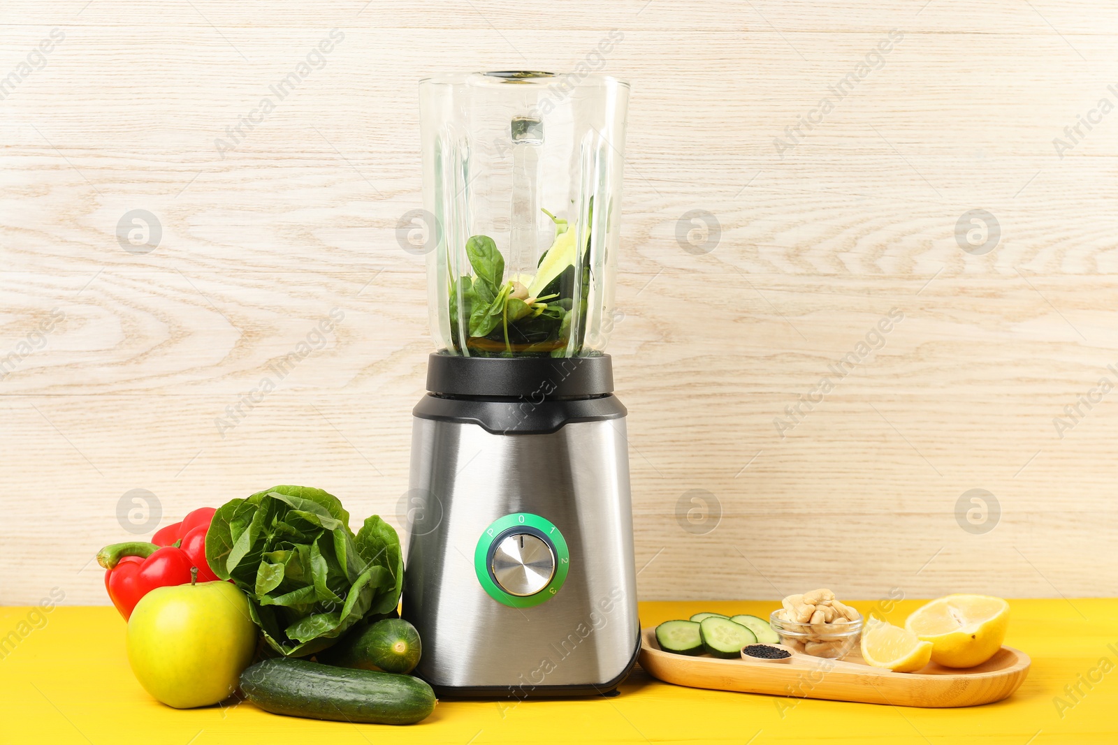 Photo of Modern blender with ingredients for smoothie on yellow wooden table