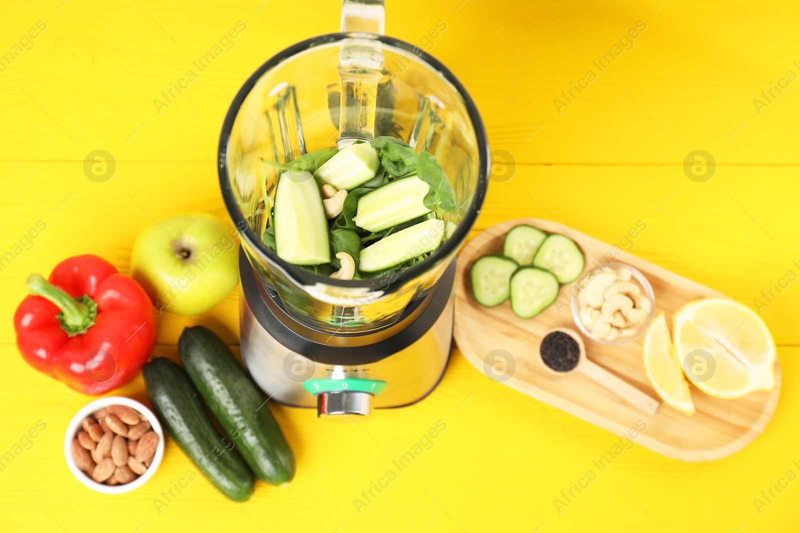 Photo of Modern blender with ingredients for smoothie on yellow wooden table