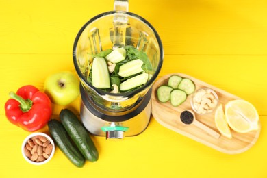 Modern blender with ingredients for smoothie on yellow wooden table