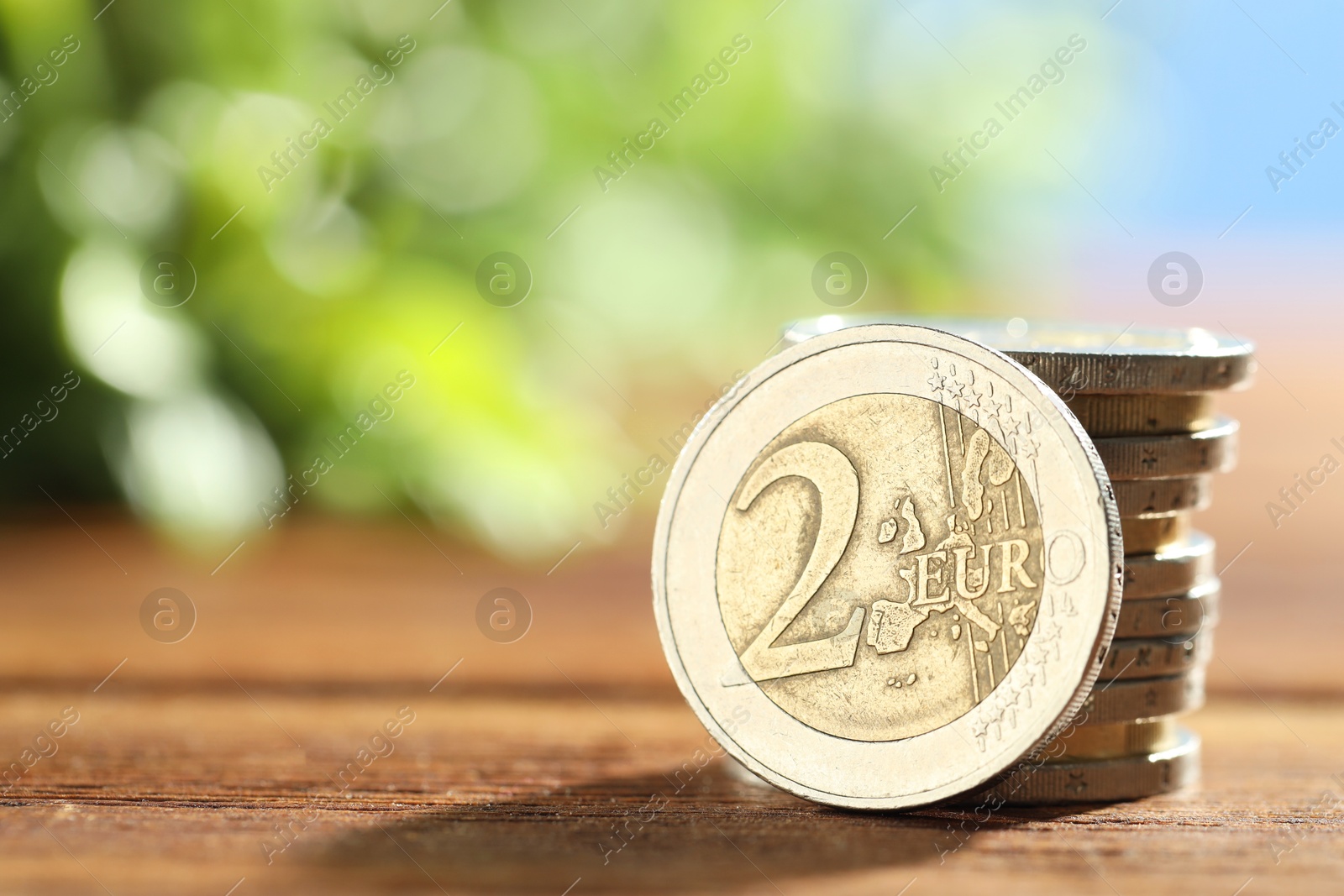 Photo of Stacked euro coins on wooden table, closeup. Space for text