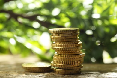 Photo of Stacked euro coins on wooden table outdoors