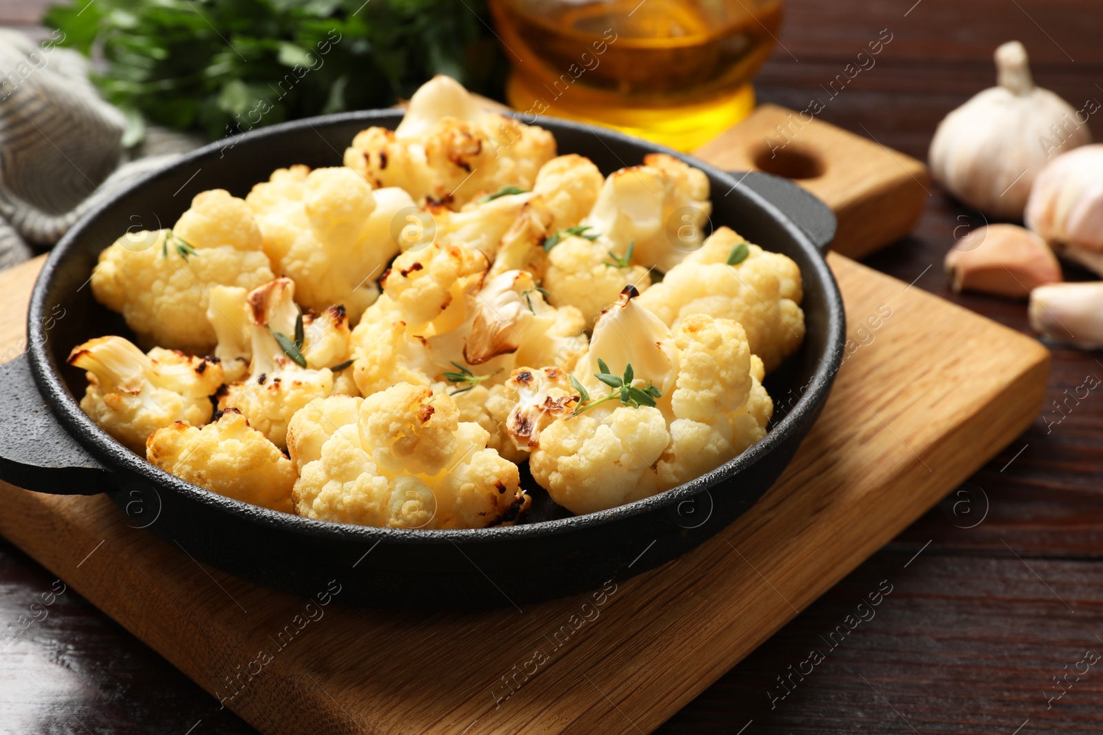 Photo of Tasty baked cauliflower in baking pan on wooden table, closeup