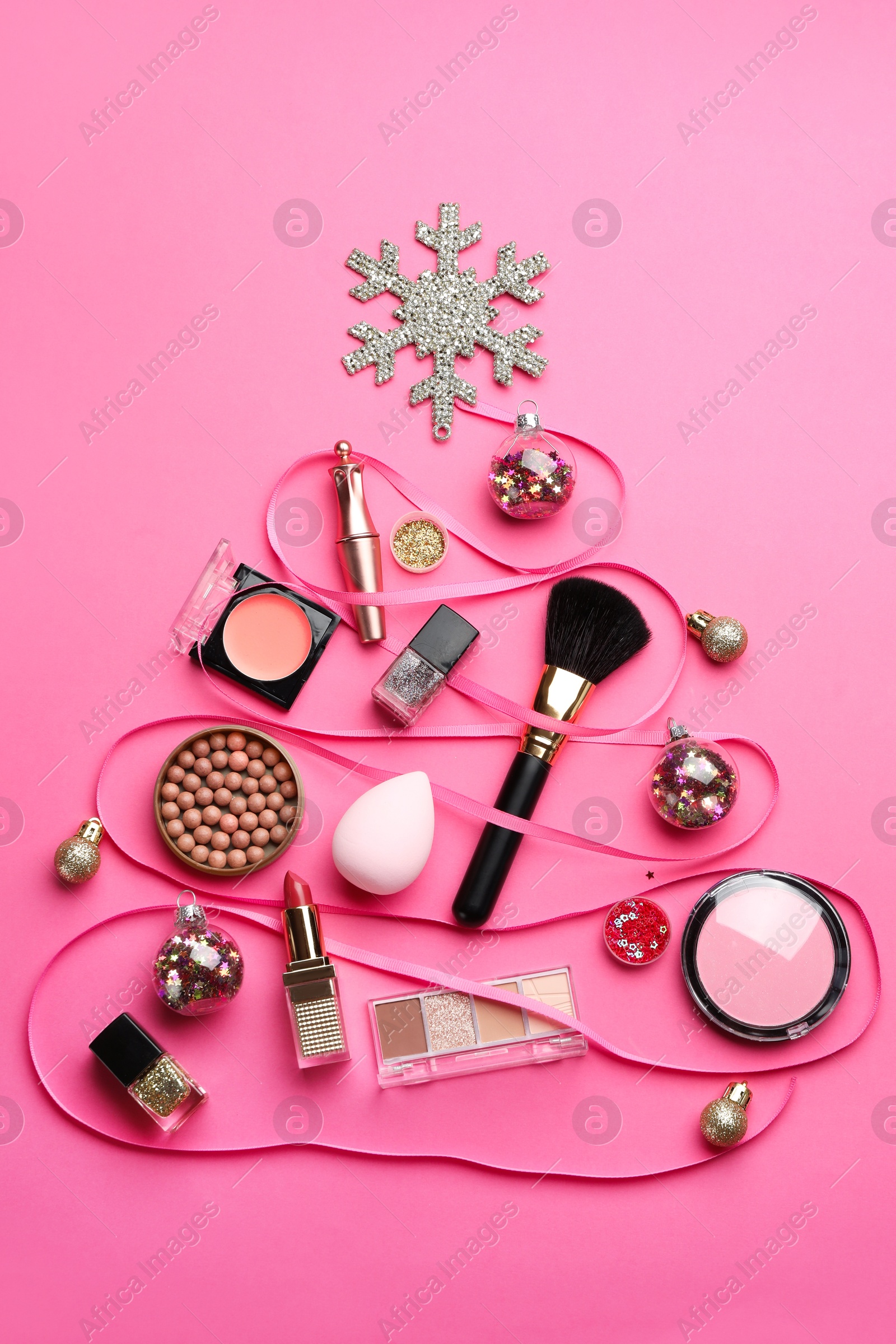 Photo of Christmas tree made of decorative cosmetic products and festive decor on pink background, flat lay