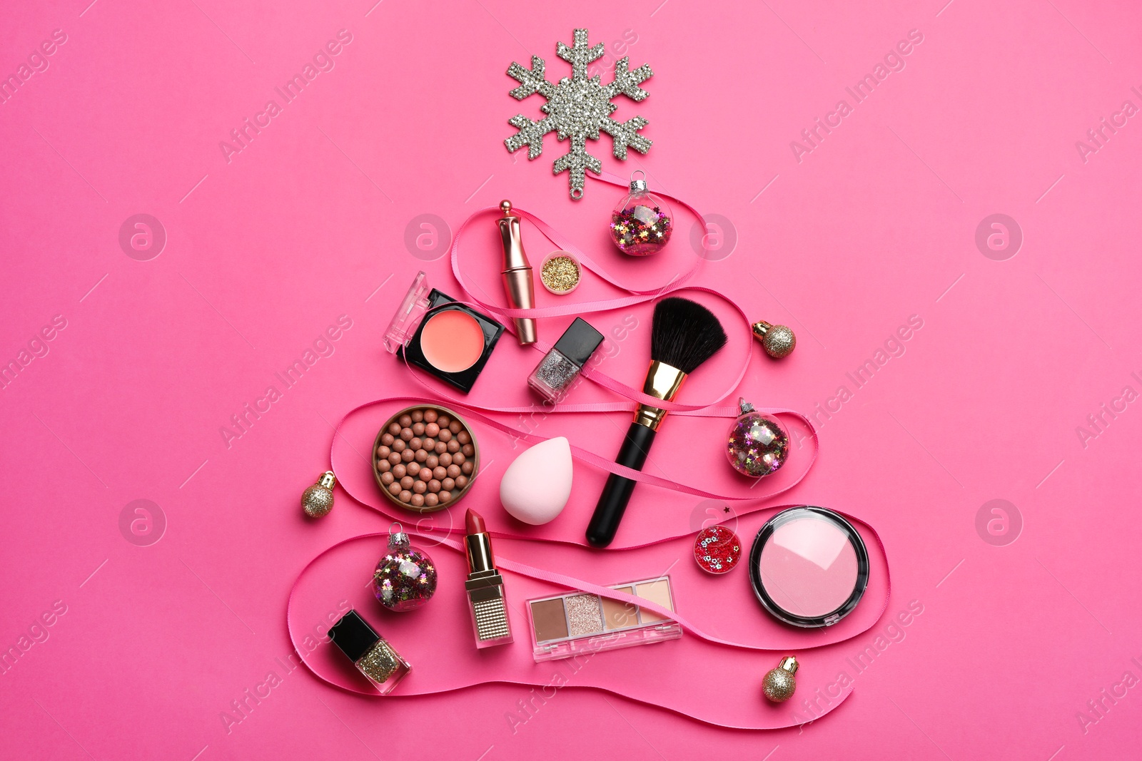 Photo of Christmas tree made of decorative cosmetic products and festive decor on pink background, flat lay