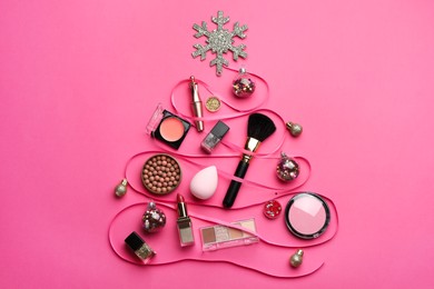 Christmas tree made of decorative cosmetic products and festive decor on pink background, flat lay