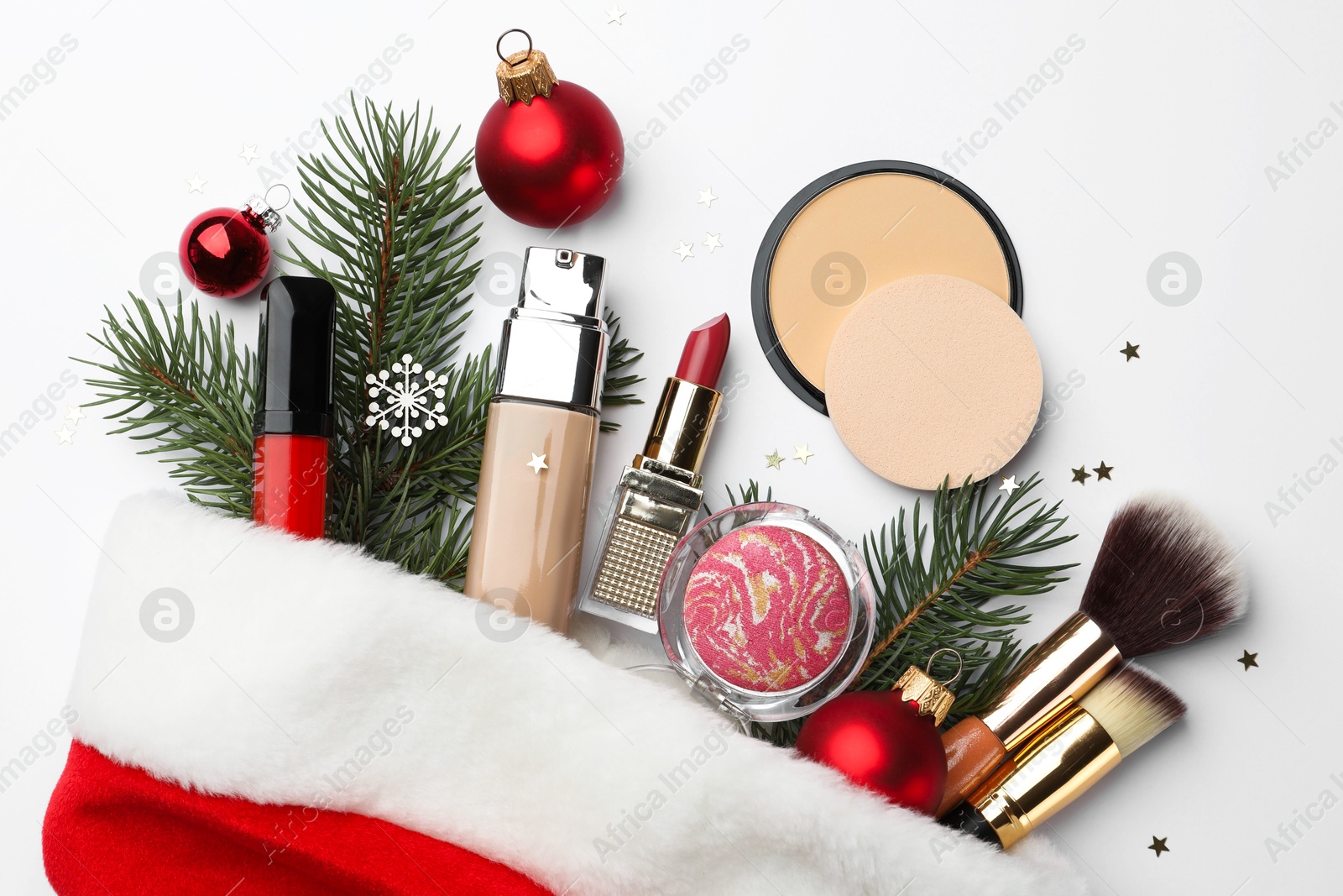 Photo of Santa hat with different decorative cosmetic products and Christmas decor on white background, top view