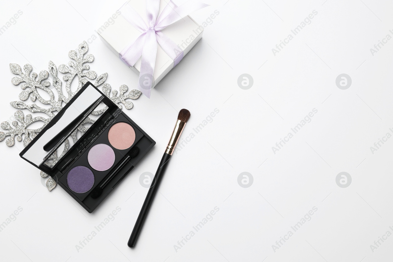 Photo of Makeup brushes, eyeshadow palette, gift box and snowflake on white background, flat lay. Space for text