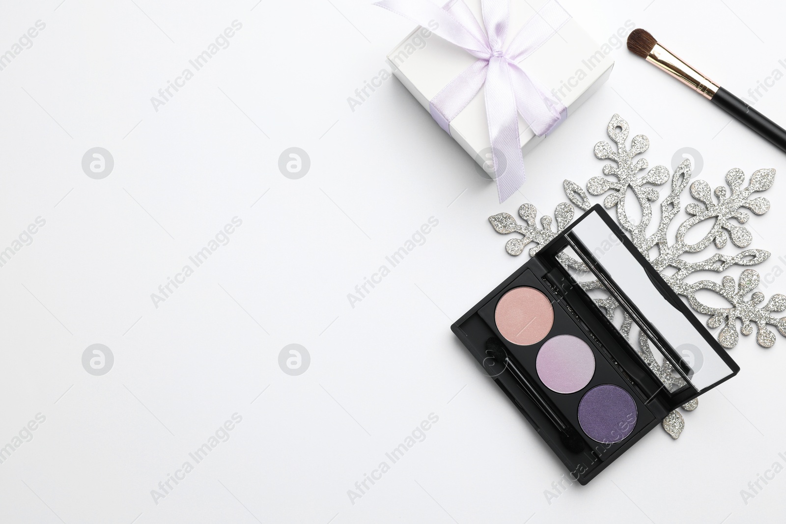 Photo of Makeup brushes, eyeshadow palette, gift box and snowflake on white background, flat lay. Space for text