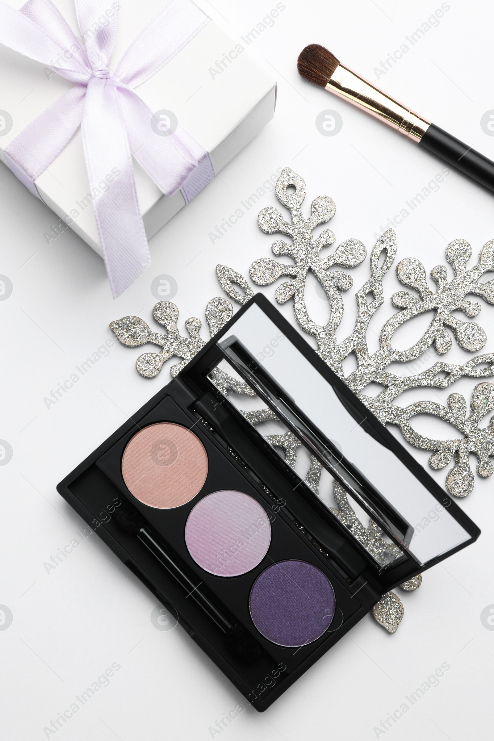 Photo of Makeup brushes, eyeshadow palette, gift box and snowflake on white background, flat lay