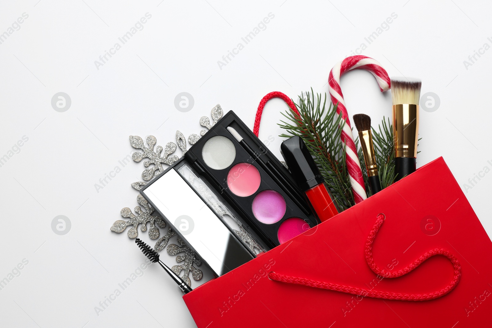 Photo of Different decorative cosmetic products in gift bag and Christmas decor on white background, top view