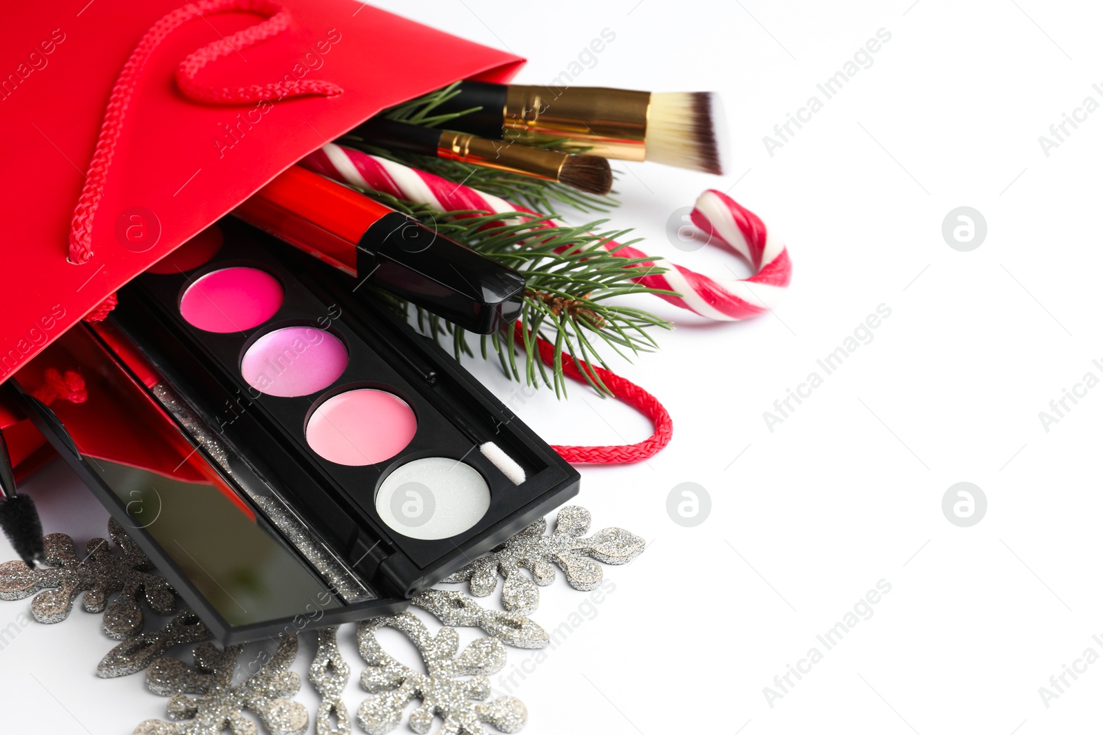 Photo of Different decorative cosmetic products in gift bag and Christmas decor on white background, closeup. Space for text