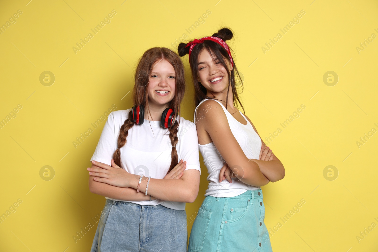 Photo of Happy teenage girls with crossed arms on yellow background